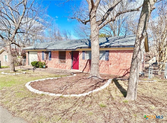 single story home with brick siding, an attached garage, and a front yard