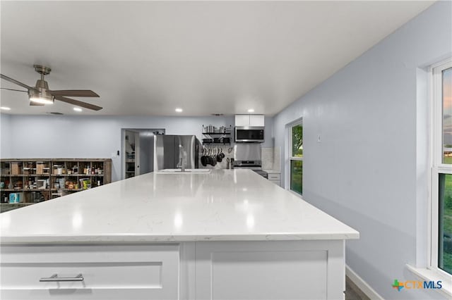 1236 County Road 7611, Devine, TX 78016 - kitchen with stainless steel appliances, white cabinets, a ceiling fan, a kitchen island, and recessed lighting
