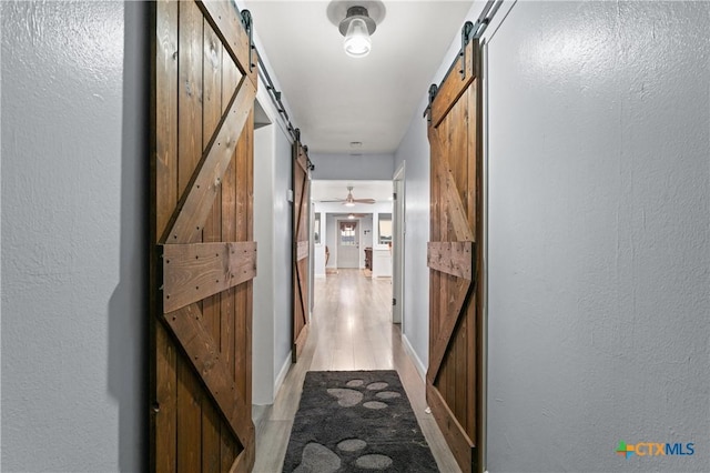 1236 County Road 7611, Devine, TX 78016 - hallway with a barn door, light wood-style flooring, and a textured wall