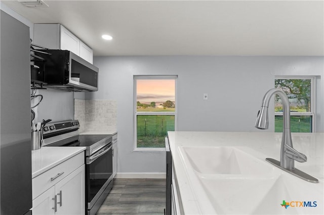 1236 County Road 7611, Devine, TX 78016 - kitchen with stainless steel appliances, white cabinetry, light countertops, backsplash, and dark wood-type flooring