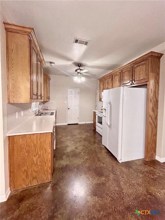 kitchen with white appliances, visible vents, light countertops, and brown cabinetry