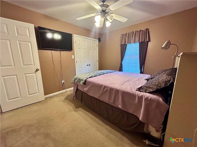 bedroom featuring baseboards, ceiling fan, a closet, and light colored carpet