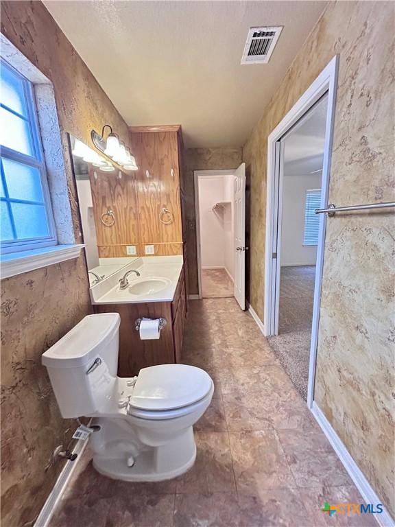 bathroom with toilet, vanity, visible vents, and baseboards