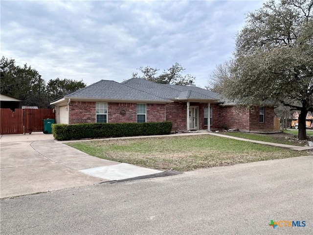 single story home featuring an attached garage, brick siding, fence, roof with shingles, and a front lawn