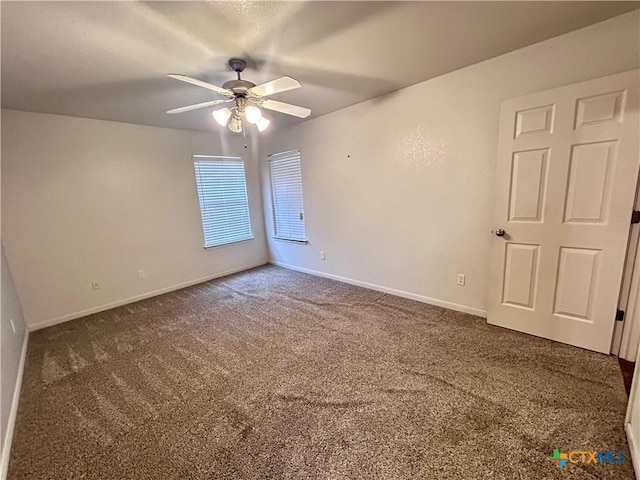 unfurnished room with dark colored carpet, ceiling fan, and baseboards