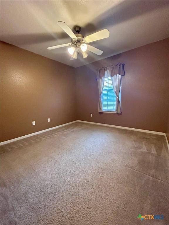 carpeted empty room with a ceiling fan and baseboards