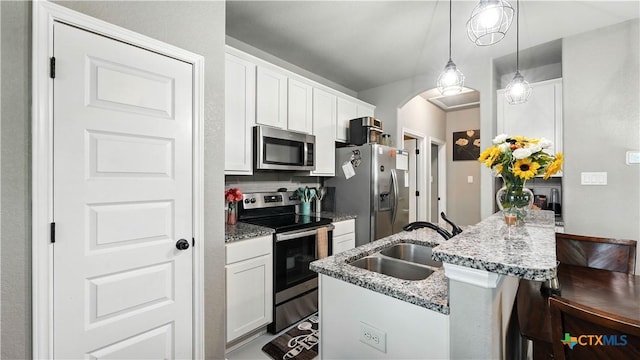 911-913 E Seideman St, Seguin, TX 78155 - kitchen featuring stainless steel appliances, a breakfast bar area, arched walkways, white cabinetry, and light stone countertops