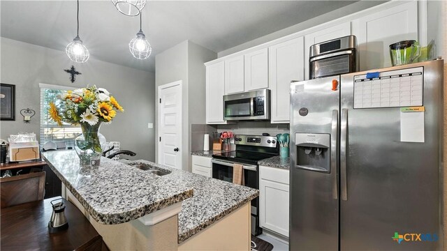 911-913 E Seideman St, Seguin, TX 78155 - kitchen featuring appliances with stainless steel finishes, light stone countertops, a center island with sink, backsplash, and white cabinets