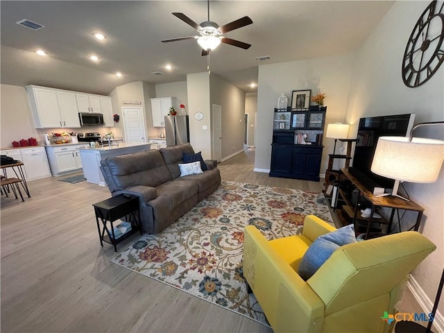 living room featuring light wood-type flooring, vaulted ceiling, and ceiling fan