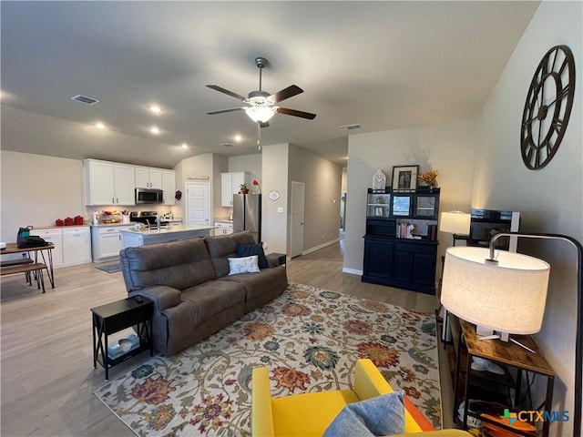 living room with light hardwood / wood-style floors, ceiling fan, and lofted ceiling