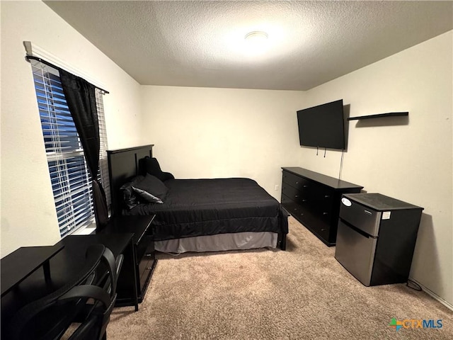 bedroom with a textured ceiling, carpet floors, and freestanding refrigerator