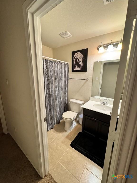 bathroom with visible vents, a shower with shower curtain, toilet, tile patterned flooring, and vanity