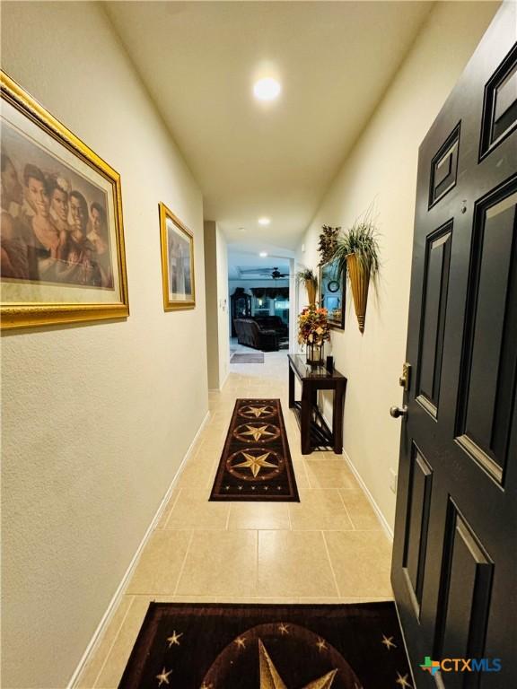 corridor with baseboards, recessed lighting, and tile patterned floors