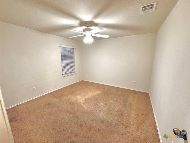 unfurnished room featuring visible vents, a ceiling fan, carpet flooring, a textured ceiling, and baseboards