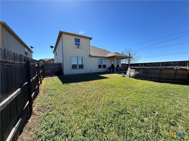 rear view of property featuring a fenced in pool, a fenced backyard, and a yard