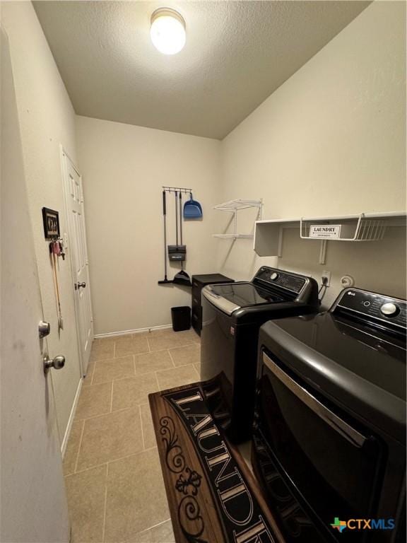 laundry area with light tile patterned floors, laundry area, separate washer and dryer, and a textured ceiling