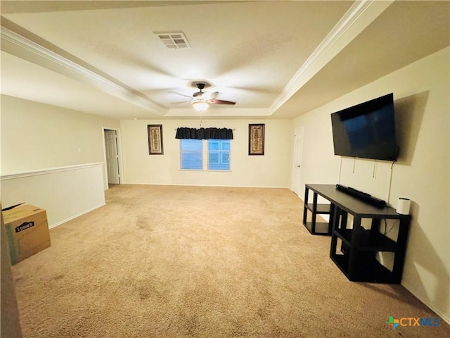 living room with visible vents, a raised ceiling, ceiling fan, crown molding, and carpet flooring