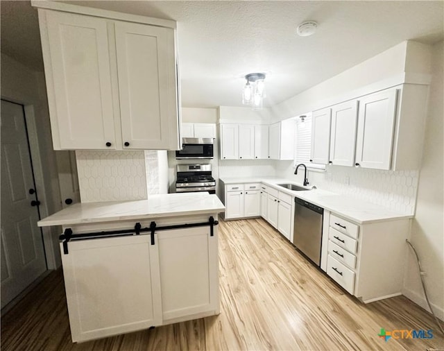 kitchen with backsplash, stainless steel appliances, white cabinetry, and sink