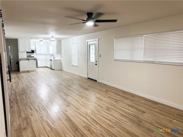 unfurnished living room featuring ceiling fan, light hardwood / wood-style floors, and sink