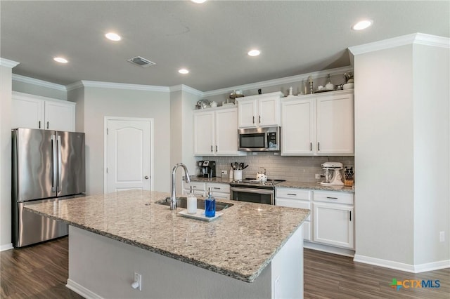 611 Hawks Shadow Dr, Temple, TX 76502 - kitchen featuring stainless steel appliances, dark wood finished floors, an island with sink, light stone countertops, and ornamental molding