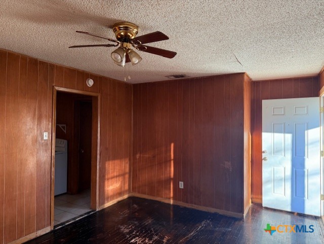 spare room with washer / dryer, ceiling fan, and wooden walls