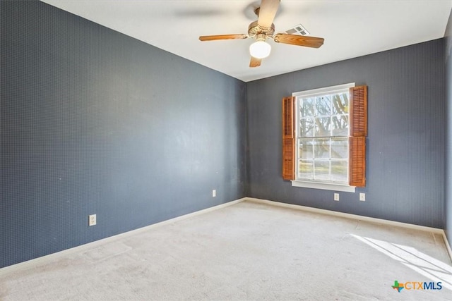 empty room featuring carpet floors, visible vents, baseboards, and a ceiling fan