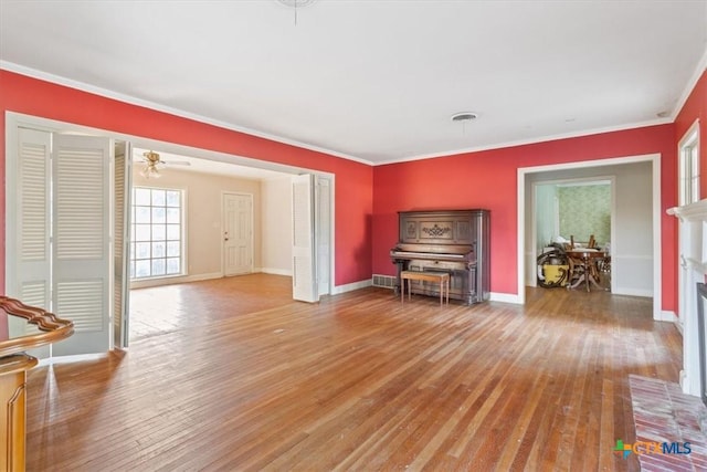 unfurnished room featuring a fireplace, visible vents, ornamental molding, wood finished floors, and baseboards