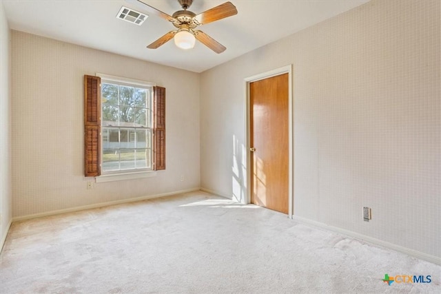 empty room featuring a ceiling fan, carpet, visible vents, and baseboards