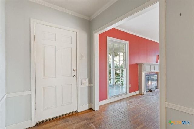 doorway to outside with hardwood / wood-style flooring, a fireplace with flush hearth, ornamental molding, and baseboards