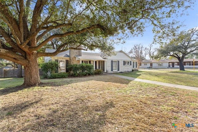 single story home featuring a chimney, fence, and a front yard