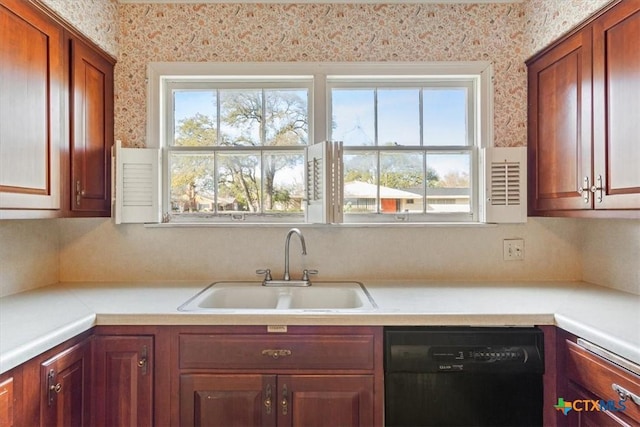 kitchen with black dishwasher, light countertops, a sink, and wallpapered walls