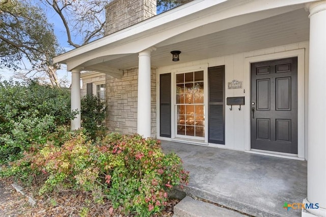 entrance to property featuring covered porch and a chimney