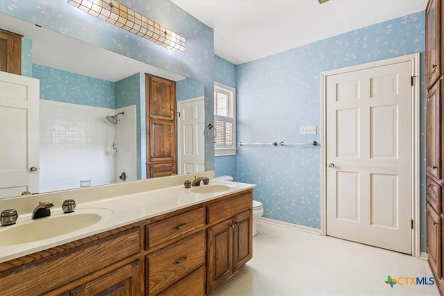 bathroom with wallpapered walls, a shower, and a sink