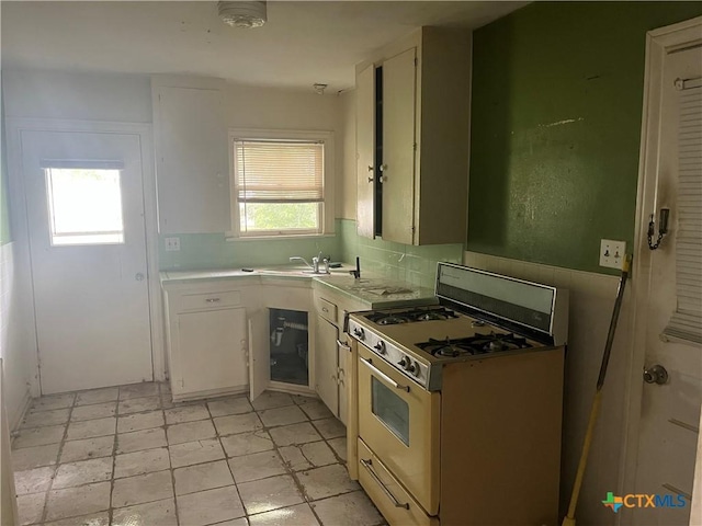406 Lariat Ln, Victoria, TX 77901 - kitchen with white cabinetry, light countertops, white range with gas stovetop, and a sink