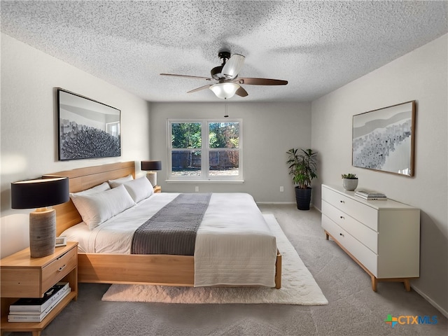 bedroom with ceiling fan, light carpet, and a textured ceiling