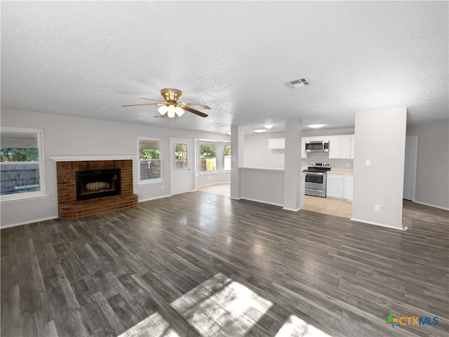 unfurnished living room with a fireplace, a textured ceiling, dark hardwood / wood-style floors, and ceiling fan