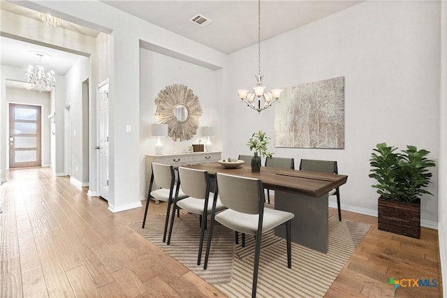 dining space with wood-type flooring and an inviting chandelier