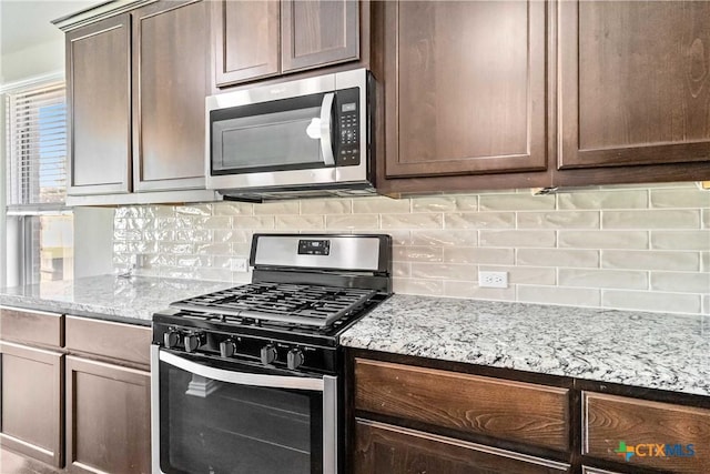 kitchen featuring light stone countertops, appliances with stainless steel finishes, and backsplash