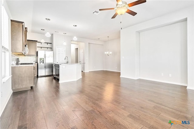 unfurnished living room featuring ceiling fan with notable chandelier, dark hardwood / wood-style flooring, and sink