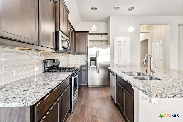 kitchen with sink, appliances with stainless steel finishes, an island with sink, pendant lighting, and decorative backsplash