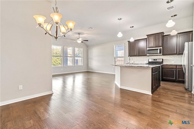 kitchen featuring stainless steel appliances, a center island with sink, decorative backsplash, and decorative light fixtures