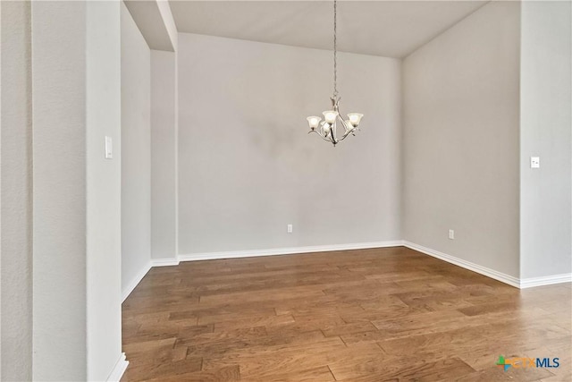 spare room with hardwood / wood-style flooring and a chandelier