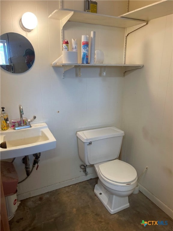 bathroom with concrete floors, toilet, and sink