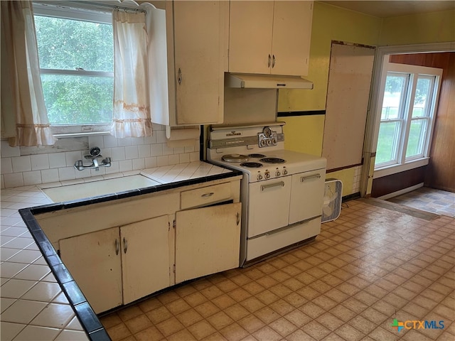 kitchen featuring white cabinets, sink, backsplash, and electric range