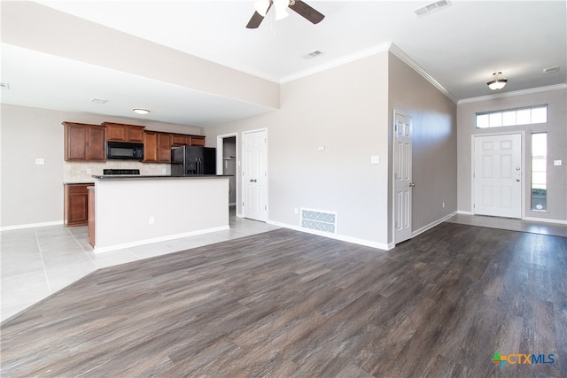 kitchen with backsplash, ornamental molding, black appliances, hardwood / wood-style floors, and a center island