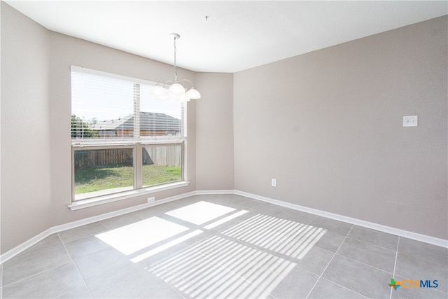 unfurnished room featuring tile patterned flooring and a chandelier