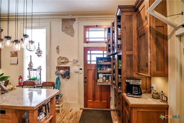 122 E Main St, Cuero, TX 77954 - kitchen featuring light countertops, brown cabinets, light wood-type flooring, crown molding, and pendant lighting