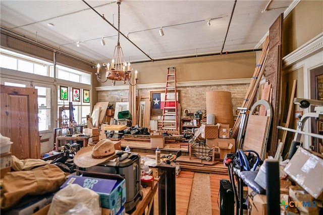 122 E Main St, Cuero, TX 77954 - miscellaneous room with wood finished floors, track lighting, a chandelier, and brick wall