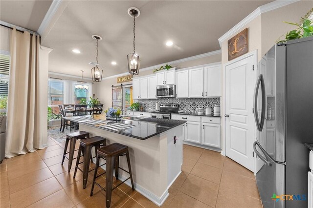 kitchen with pendant lighting, white cabinets, crown molding, sink, and appliances with stainless steel finishes