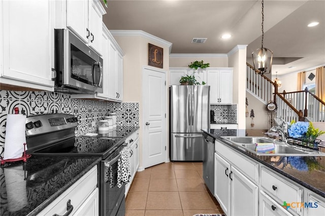 kitchen with sink, white cabinets, stainless steel appliances, and decorative light fixtures